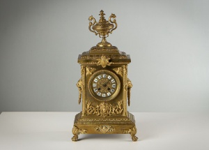 картинка Антикварные каминные часы в золоченом корпусе, украшенном резными деталями салоне старинных вещей "Шебби" являющийся официальным дистрибьютором в России и Беларуси